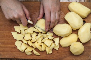 Kadın eli üzerinde ahşap boa patates Dilimleme bir bıçak kesim ile