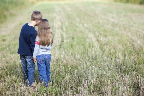 Niño y niña de pie tomados de la mano mirando a Hor — Foto de Stock