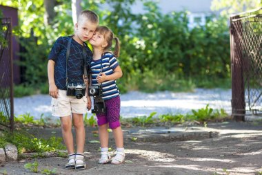 Küçük bir çocuk ve bir kız ayakta iki vintage kameralar wit