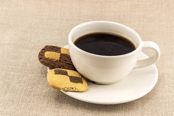 Xícara de café com xadrez biscoito como biscoitos em saco de serapilheira — Fotografia de Stock