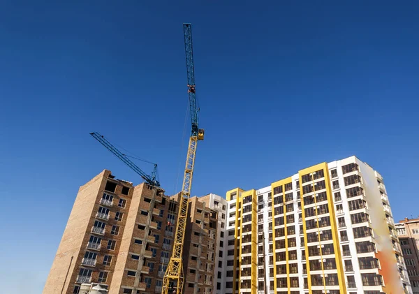 Guindaste e arranha-céus em construção contra o céu azul — Fotografia de Stock