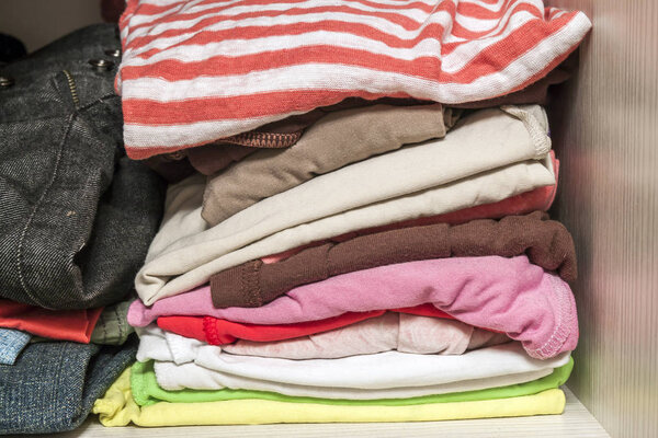 A stack of knitted warm woolen clothes in wardrobe close up