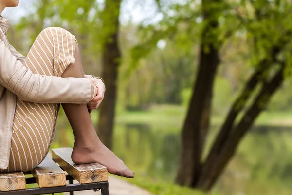 Ноги красивой молодой женщины сидят на скамейке в парке . — стоковое фото