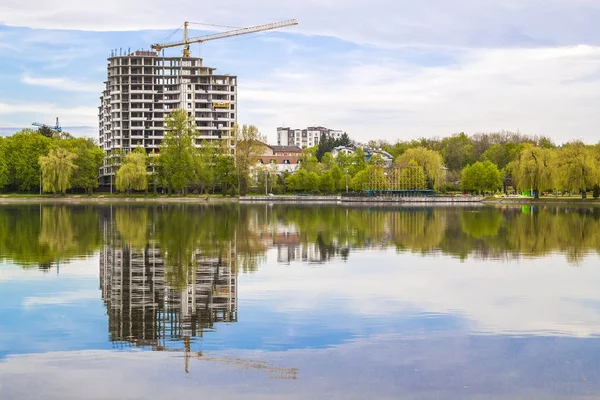 New modern skyscraper under construction on the bank of a lake.