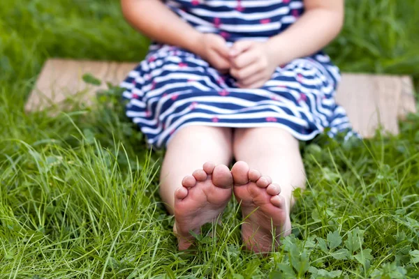 在绿色草地上的小女孩的脚的特写 — 图库照片