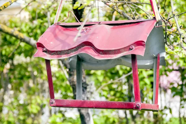 Alimentador vermelho de metal para pássaros. Fundo verde . — Fotografia de Stock