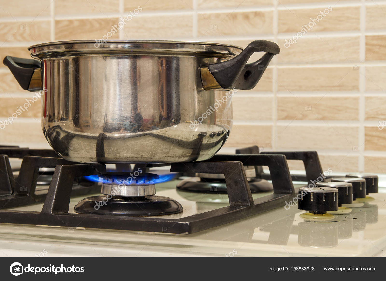 Metal cooking pot standing on kitchen stove with flame. Stock Photo by  ©bilanol.i.ua 158883928