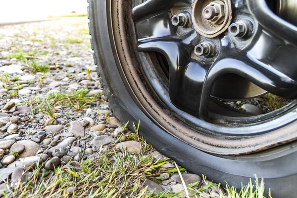 Close-up de pneu furado em um carro na estrada de cascalho . — Fotografia de Stock