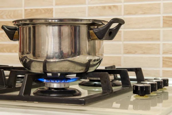 Metal cooking pot standing on kitchen stove with flame. — Stock Photo, Image