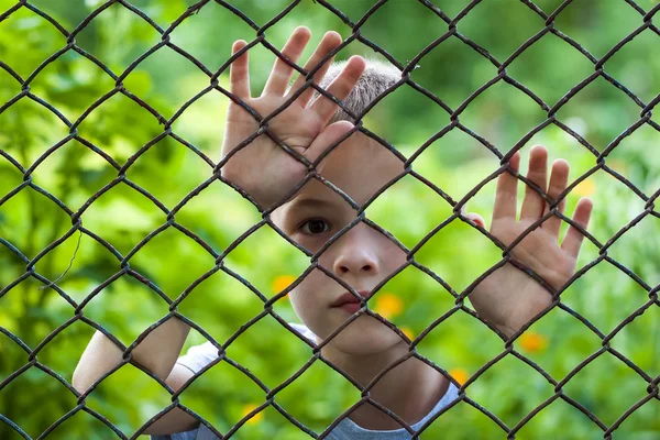 Imagem abstrata de um rapazinho atrás de uma cerca de arame. Foto — Fotografia de Stock