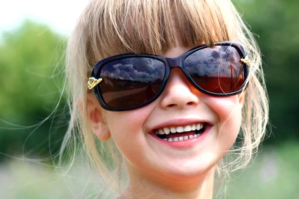 Ganska leende liten flicka i stora solglasögon — Stockfoto