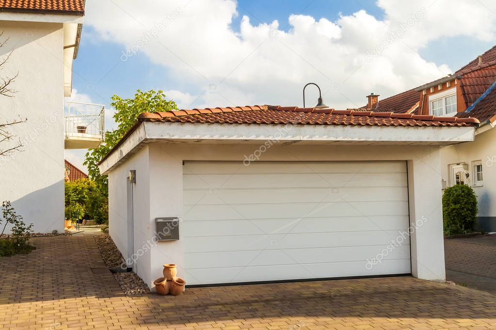 Detached white garage with orange brick tile roof