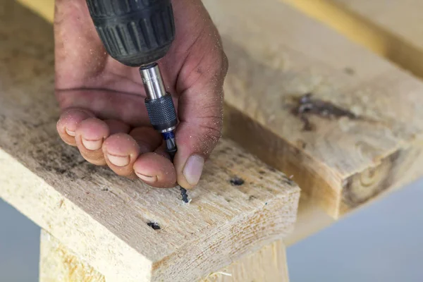 Mano de los trabajadores con destornillador eléctrico atornillando un tornillo en woo — Foto de Stock