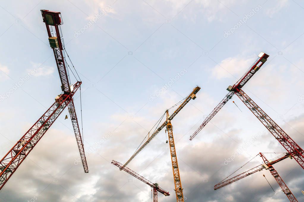 Construction tower cranes against blue sky. Industrial construct