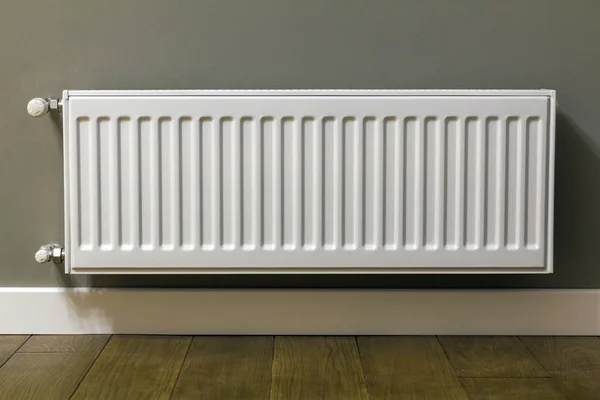 Radiador de aquecimento branco na parede em um apartamento com piso de madeira — Fotografia de Stock