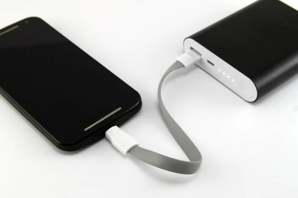 Carga de Smartphone desde el banco de energía negro aislado en la espalda blanca —  Fotos de Stock