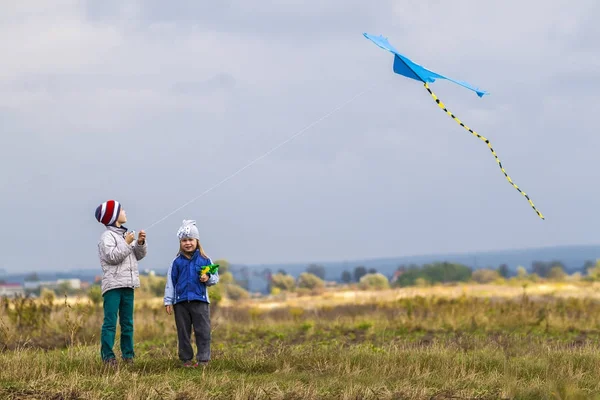 Two little children boy and girl playing outside with a kite — Stock Photo, Image