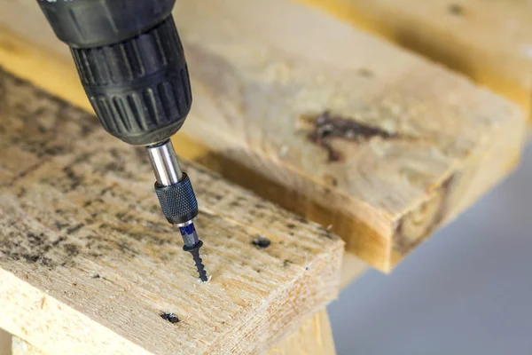 Workers hand with electric screwdriver screwing a screw into woo — Stock Photo, Image