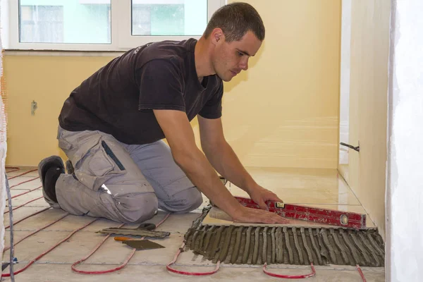 Worker installing floor tiles. Ceramic tiles and tools for tiler