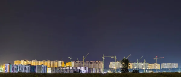 Panorama night view of many building cranes at construction site Stock Image