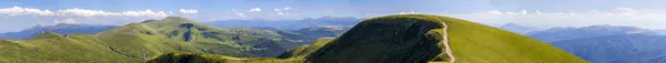 Panorama de colinas verdes em montanhas de verão com estrada de cascalho para — Fotografia de Stock