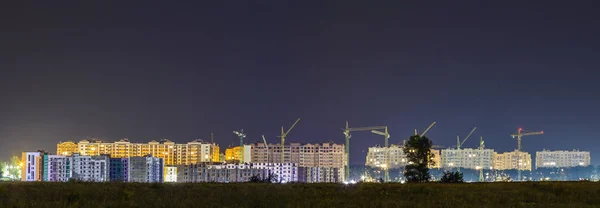 Panorama night view of many building cranes at construction site
