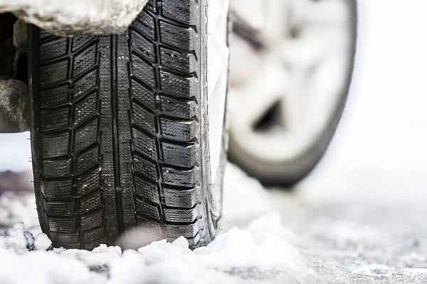 Nahaufnahme eines Autorads mit Winterreifen auf schneeglatter Straße — Stockfoto