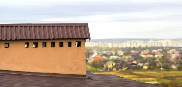 Труба на крыше нового построенного дома с видом на город внизу — стоковое фото