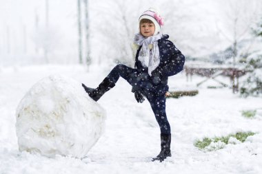 Küçük kız açık havada büyük kar topu yakınındaki kışın