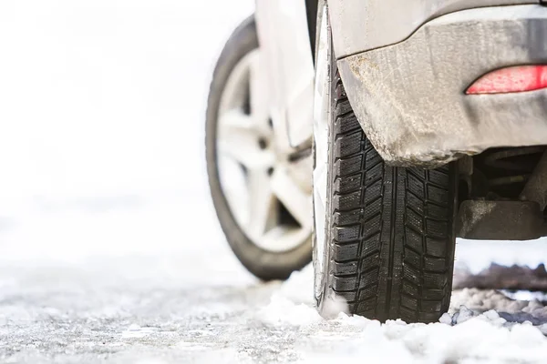 Nahaufnahme eines Autorads mit Winterreifen auf schneeglatter Straße — Stockfoto