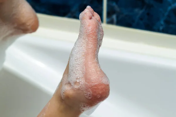 Влажные ноги с морщинистой кожей и мыльными пузырями в ванной. Гигиена и — стоковое фото