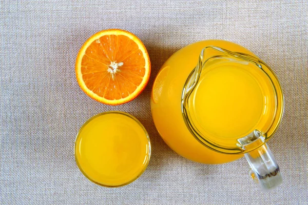 Jug and glass of orange juice and ripe oranges from above, top v — Stock Photo, Image