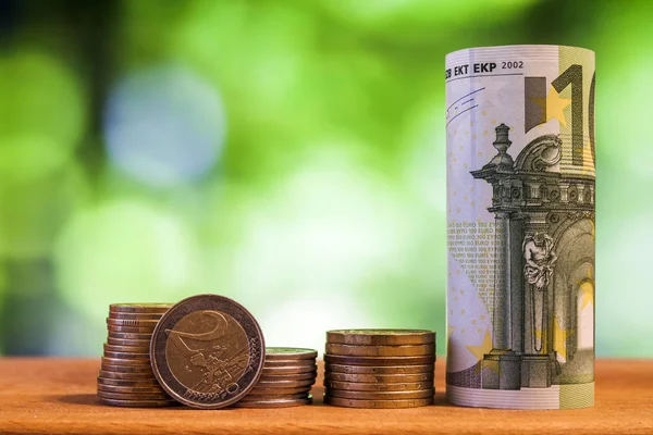 Billete rodado de cien euros con monedas en euros sobre madera — Foto de Stock