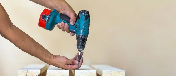 La mano del trabajador atornilla el tornillo en la tabla de madera con los cordones — Foto de Stock