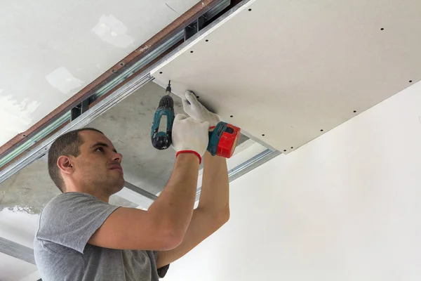 Pracownik budowlany zamontować sufit podwieszany z płyt gipsowo-kartonowych — Zdjęcie stockowe