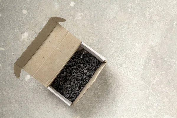 Imagem de close-up de muitos pequenos parafusos pretos no fundo de concreto — Fotografia de Stock