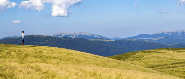 Randonneur solitaire debout sur une large colline offrant une vue sur la montagne — Photo