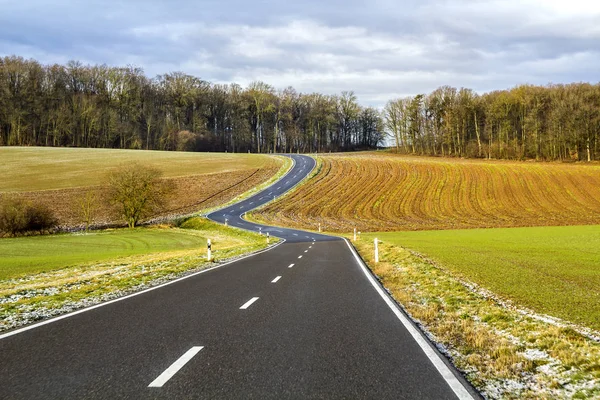 Empty black asphalt road between green fields — Stock Photo, Image