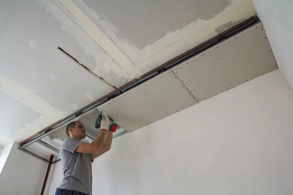 Trabajador de la construcción montar un techo suspendido con paneles de yeso un — Foto de Stock