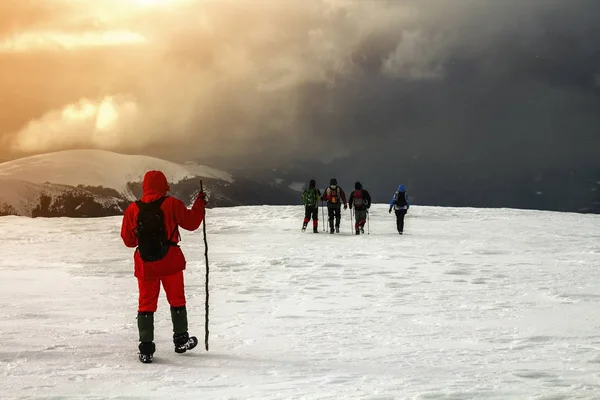 Turistas excursionistas en invierno montañas cubiertas de nieve y cl dramático —  Fotos de Stock