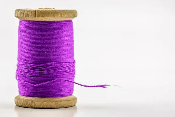 Reel or spool of violet sewing thread isolated on white. Shallow — Stock Photo, Image