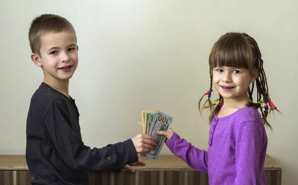 Dos niños y niñas jugando con dinero en dólares . — Foto de Stock