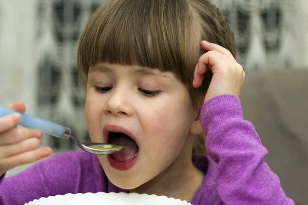 Menina criança comendo sopa de um prato com uma colher — Fotografia de Stock