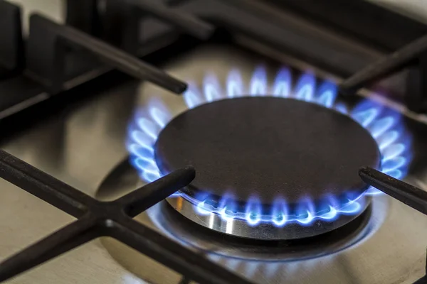 Brûlure de gaz naturel sur cuisinière à gaz de cuisine dans le noir. Panneau en acier avec brûleur à anneau de gaz sur fond noir, prise de vue rapprochée — Photo