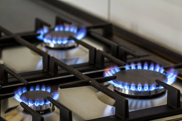 Природный газ горит на кухне газовая плита в темноте. Панель из стали с газовой горелкой на черном фоне, крупным планом
