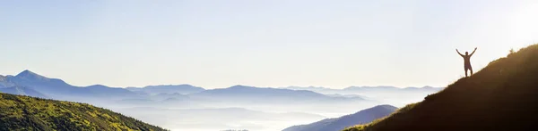 Panorama de jóvenes exitosos senderista silueta brazos abiertos en la cima de la montaña . — Foto de Stock