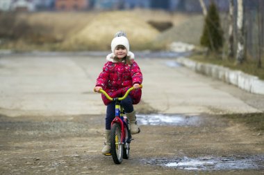 bir parkta güzel gülümseyen küçük kız binicilik bisiklet