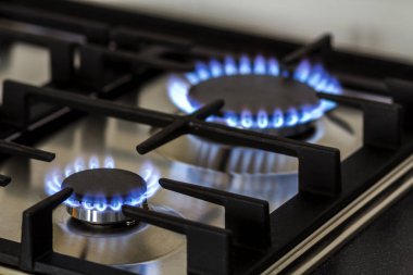 Natural gas burning on kitchen gas stove in the dark. Panel from steel with a gas ring burner on a black background, close-up shooting clipart