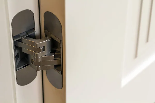 Nowe nowoczesne metalowe drzwi zawiasowe na białych drewnianych drzwiach — Zdjęcie stockowe