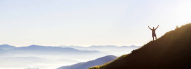 Genç başarılı adam uzun yürüyüşe çıkan kimse siluet Panoraması açık silah dağ tepe üzerinde.